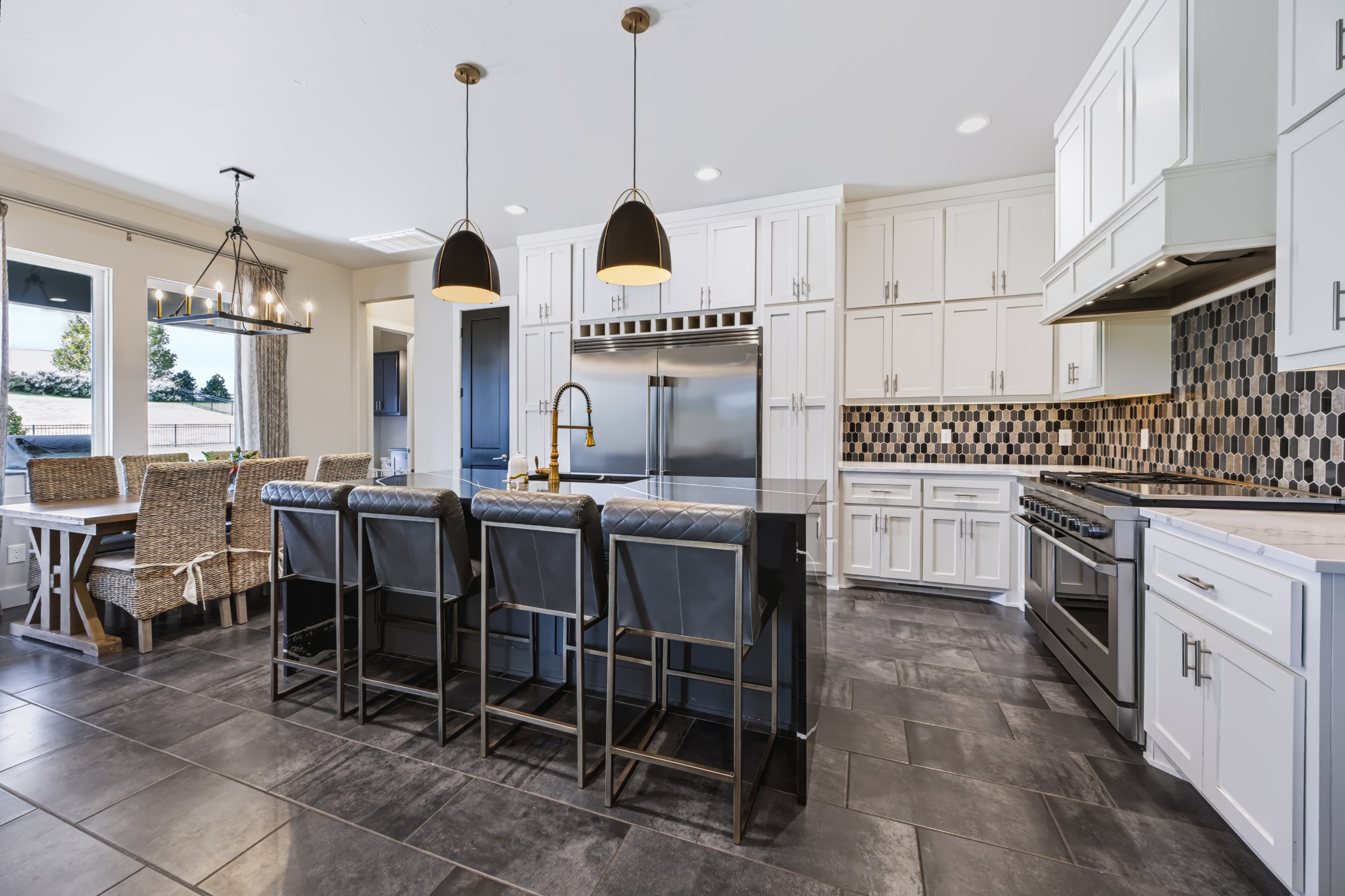 Chef's kitchen with black island, white cabinetry, and geometric backsplash at 21458 S Sawtooth Cir